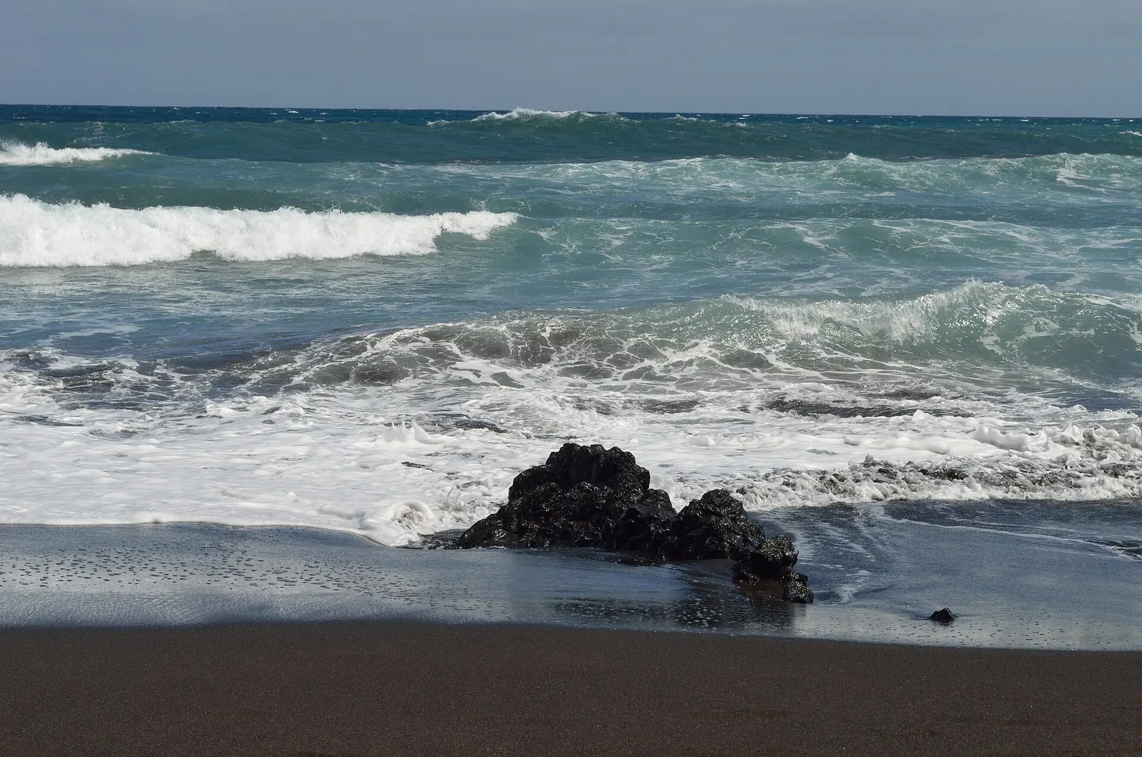 Waves breaking on a black volcanic sand beach in Tenerife